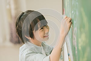 Asian boy happy smile enjoy education at school in classroom writing answer at chalkboards