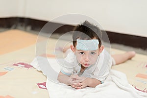 Asian boy having fever .  kid attach cooling gel pad on his forehead for relief fever