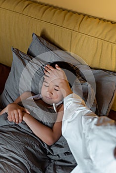 Asian boy having temperature and lying