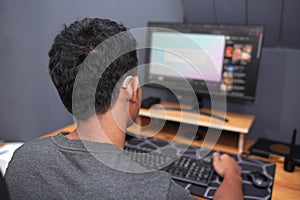 Asian boy with hearing aid device using computer