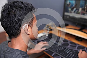 Asian boy with hearing aid device using computer
