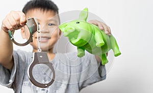 Asian boy holding piggy bank and handcuff choice between good education and crime.