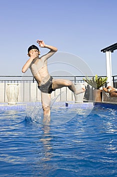 Asian boy jumpin into swimming pool