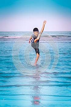 Asian boy kicking splashing water on a Beach for Children Summer Vacation happiness concept