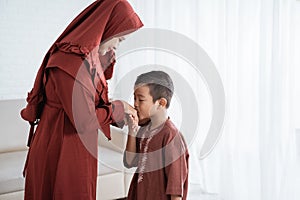 Asian boy kissing his mother`s hand when celebrating Happy Eid Ul-