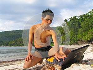 Asian boy with laptop on beach