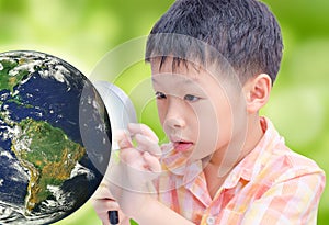 Asian boy looking at glowing globe by magnifying glass