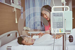 Asian boy lying on sickbed with infusion pump intravenous IV dri