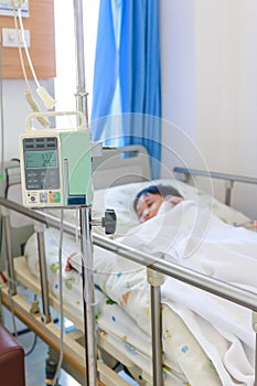 Asian boy lying on sickbed with infusion pump intravenous IV drip.