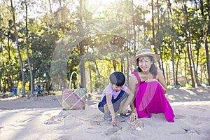 Asian boy and mom woman relaxing on tropical beach, they are njoy freedom and fresh air, wearing stylish hat and clothes. Happy