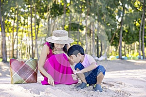 Asian boy and mom woman relaxing on tropical beach, they are njoy freedom and fresh air, wearing stylish hat and clothes. Happy