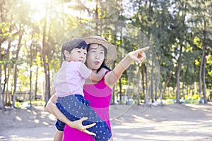 Asian boy and mom woman relaxing on tropical beach, they are njoy freedom and fresh air, wearing stylish hat and clothes. Happy