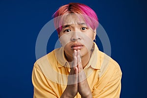 Asian boy with pink hair frowning while payer gesture