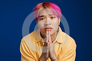 Asian boy with pink hair frowning while payer gesture photo