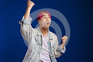 Asian boy with pink hair screaming while making winner gesture
