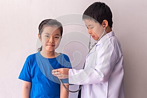 Asian boy playing doctor and listening girl with stethoscope