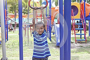 Asian boy playing monkey bars in the playground.