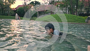 Asian boy is playing with Snorkel Mask in a swimming pool