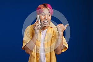 Asian boy pointing finger aside while talking on cellphone