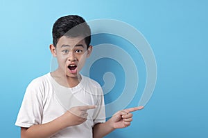 Asian boy presenting pointing something on his side with copy space