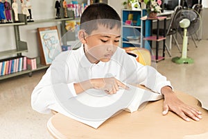 Asian boy reading a book .