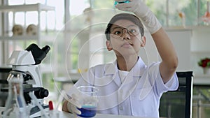 Asian boy researches blue liquid in chemistry lesson at laboratory