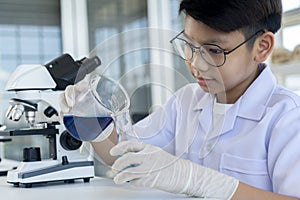 Asian boy researches blue liquid in chemistry lesson at laboratory