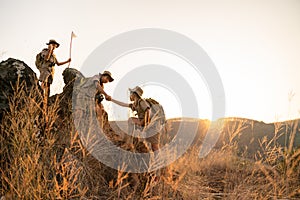 Asian boy scout teams pull their hands up a rocky cliff during a long journey. Unity and teamwork building concept