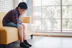 Asian boy sitting alone on sofa feeling sad