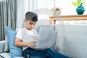 Asian boy sitting open notebook, studying online morning, sitting on living room sofa house, looks determined to study, When class