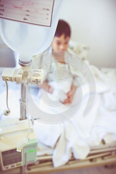 Asian boy sitting on sickbed with infusion pump intravenous IV d