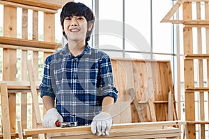 Asian boy standing in carpentry workshop.