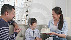Asian boy is surprised with birthday cake and celebrates party with family.
