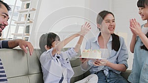 Asian boy is surprised with birthday cake and celebrates party with family.