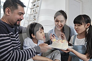 Asian boy is surprised with birthday cake and celebrates party with family