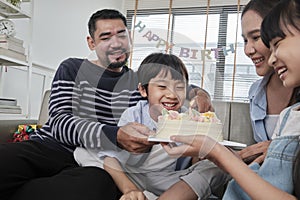 Asian boy is surprised with birthday cake and celebrates party with family