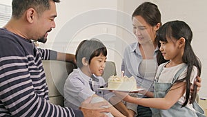 Asian boy is surprised with birthday cake and celebrates party with family.