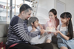 Asian boy is surprised with birthday cake and celebrates party with family