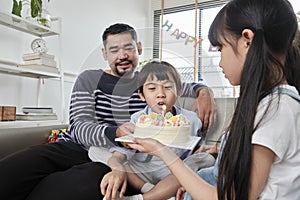 Asian boy is surprised with birthday cake and celebrates party with family