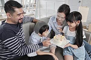 Asian boy is surprised with birthday cake and celebrates party with family