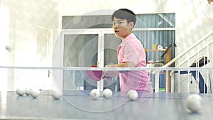 Asian boy teen practise table tennis from robot pingpong machine,