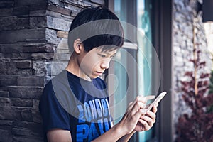 Asian boy teenager using smartphone, outdoor daylight.