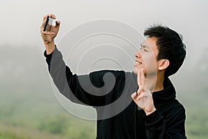 Asian boy teenager wearing black winter clothing Stand to take pictures of yourself with a mobile phone On the road along the