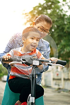 Asian boy try to riding home bicycle with mother
