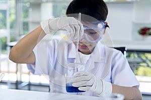 Asian boy use glass bulb drop dark blue in beaker