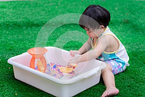 Asian boy are using toys to scoop colorful water beads. Son learns his senses through play.