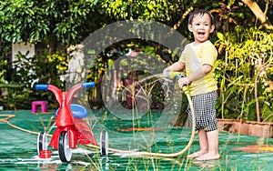 Asian boy washing red bicycle by green water sprayer