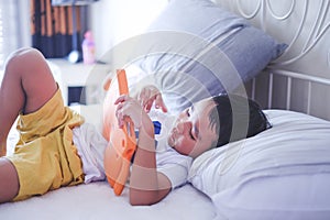 Asian boy watching online video on bed