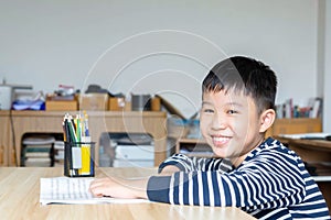 Asian boy who are studying in elementary school reading and doing homework by himself at home