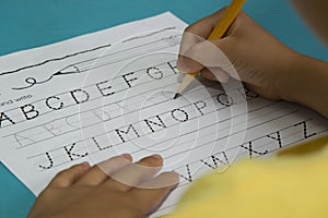 Asian boy writes letter G with a yellow pencil